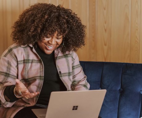 A smiling woman on a video call from her sofa